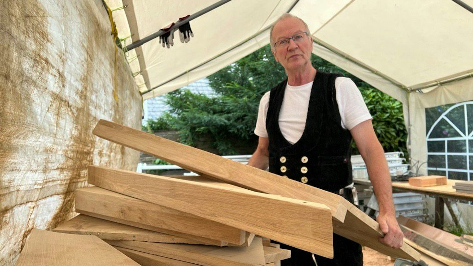 Der pensionierte Zimmerermeister Gerd Ribbeck im Werkstatts-Zelt neben dem sanierten Haus.