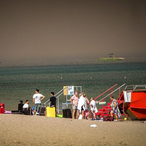 Touristen stehen an einem Strand, wohin sie wegen eines Waldbrandes auf der griechischen Insel Rhodos in Sicherheit gebracht worden sind. Die aktuelle Hitzewelle in Südeuropa lässt die Temperatur des Mittelmeers auf Höchstwerte steigen.