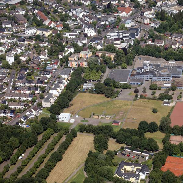 Das 1973 gebaute Schulgebäude der Integrierten Gesamtschule Paffrath. Davor das Sportgelände, ringsherum Wohnhäuser.