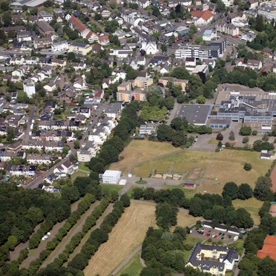 Das 1973 gebaute Schulgebäude der Integrierten Gesamtschule Paffrath. Davor das Sportgelände, ringsherum Wohnhäuser.