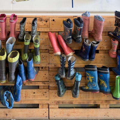 Gummistiefel hängen an einer Palettenwand in der Kindertagesstätte