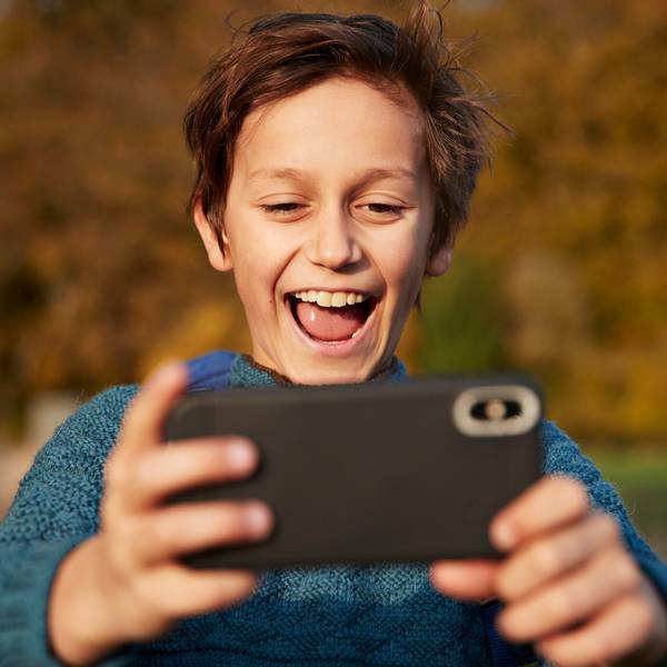 Ein Junge schaut glücklich auf sein Handy.