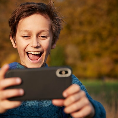 Ein Junge schaut glücklich auf sein Handy.