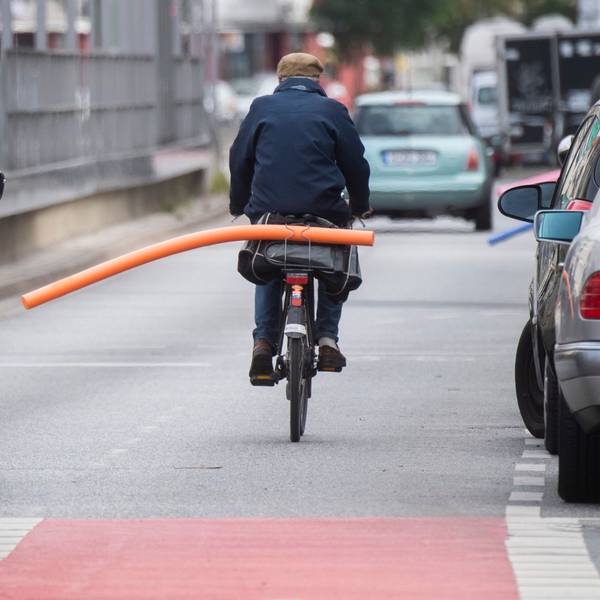 Ein Fahrradfahrer hat eine Schwimmnudel auf seinen Gepäckträger geklemmt. Damit will er auf den nötigen Sicherheitsabstand im Straßenverkehr hinweisen.