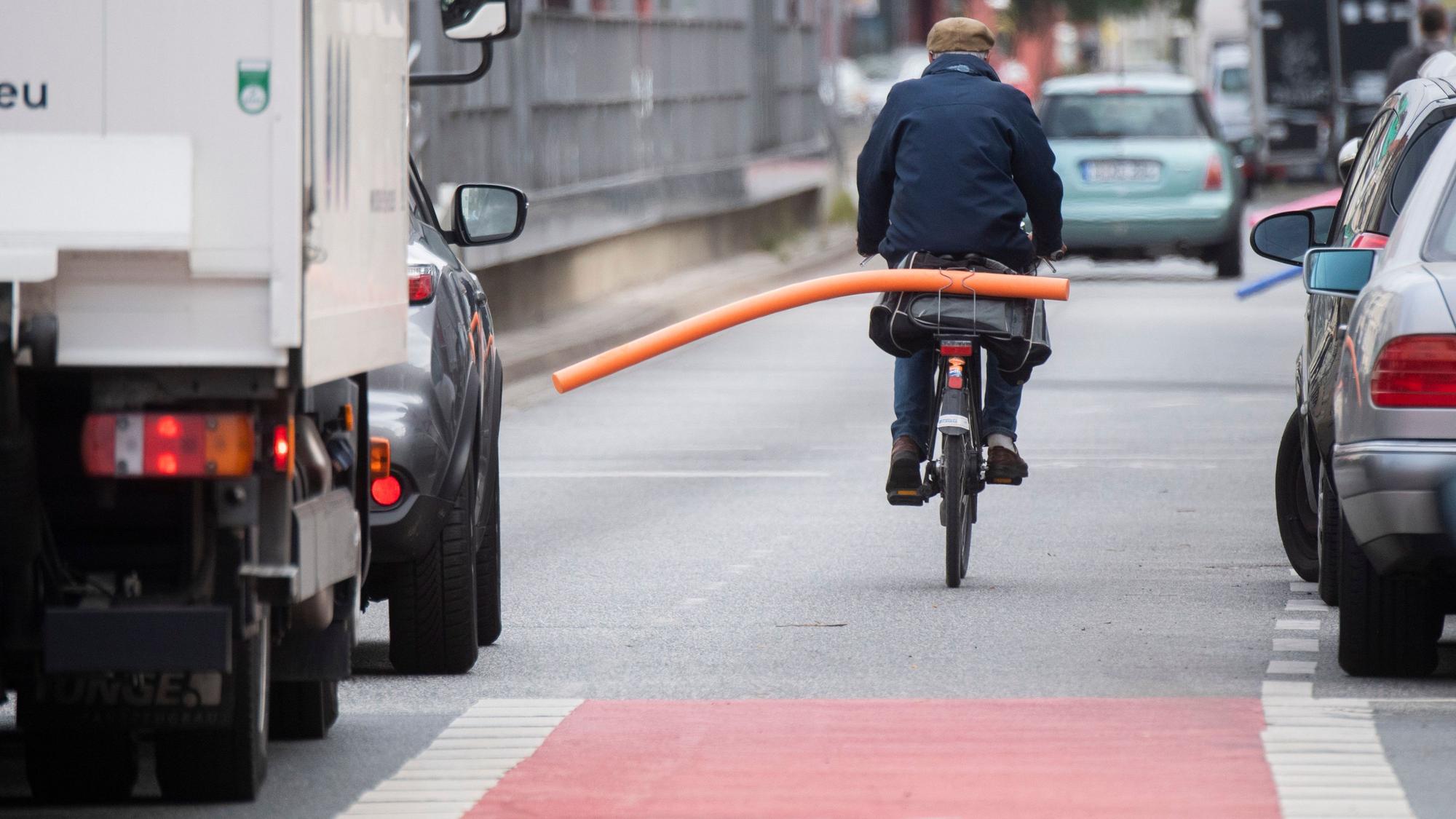 Ein Fahrradfahrer hat eine Schwimmnudel auf seinen Gepäckträger geklemmt. Damit will er auf den nötigen Sicherheitsabstand im Straßenverkehr hinweisen.