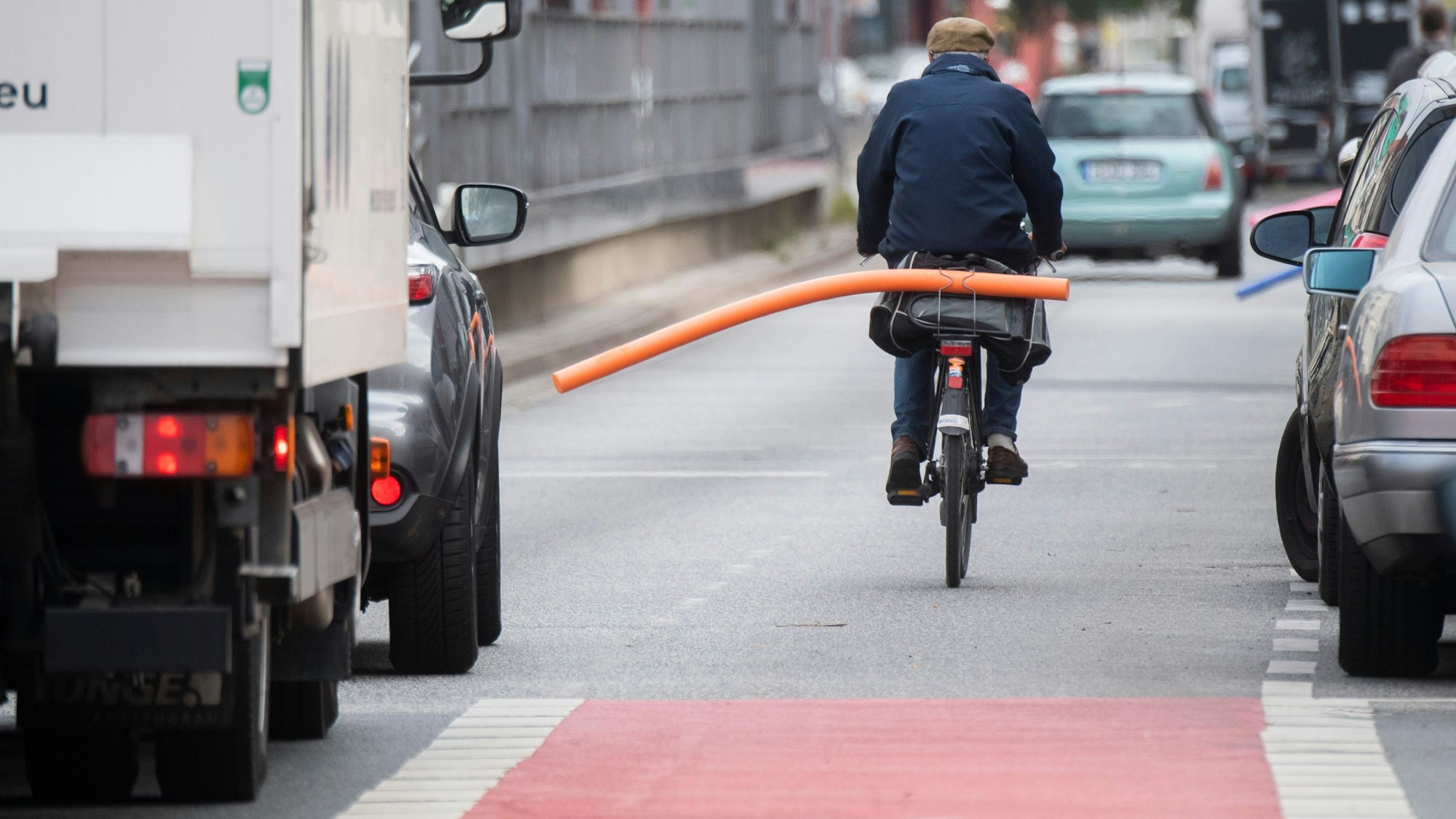 Ein Fahrradfahrer hat eine Schwimmnudel auf seinen Gepäckträger geklemmt. Damit will er auf den nötigen Sicherheitsabstand im Straßenverkehr hinweisen.