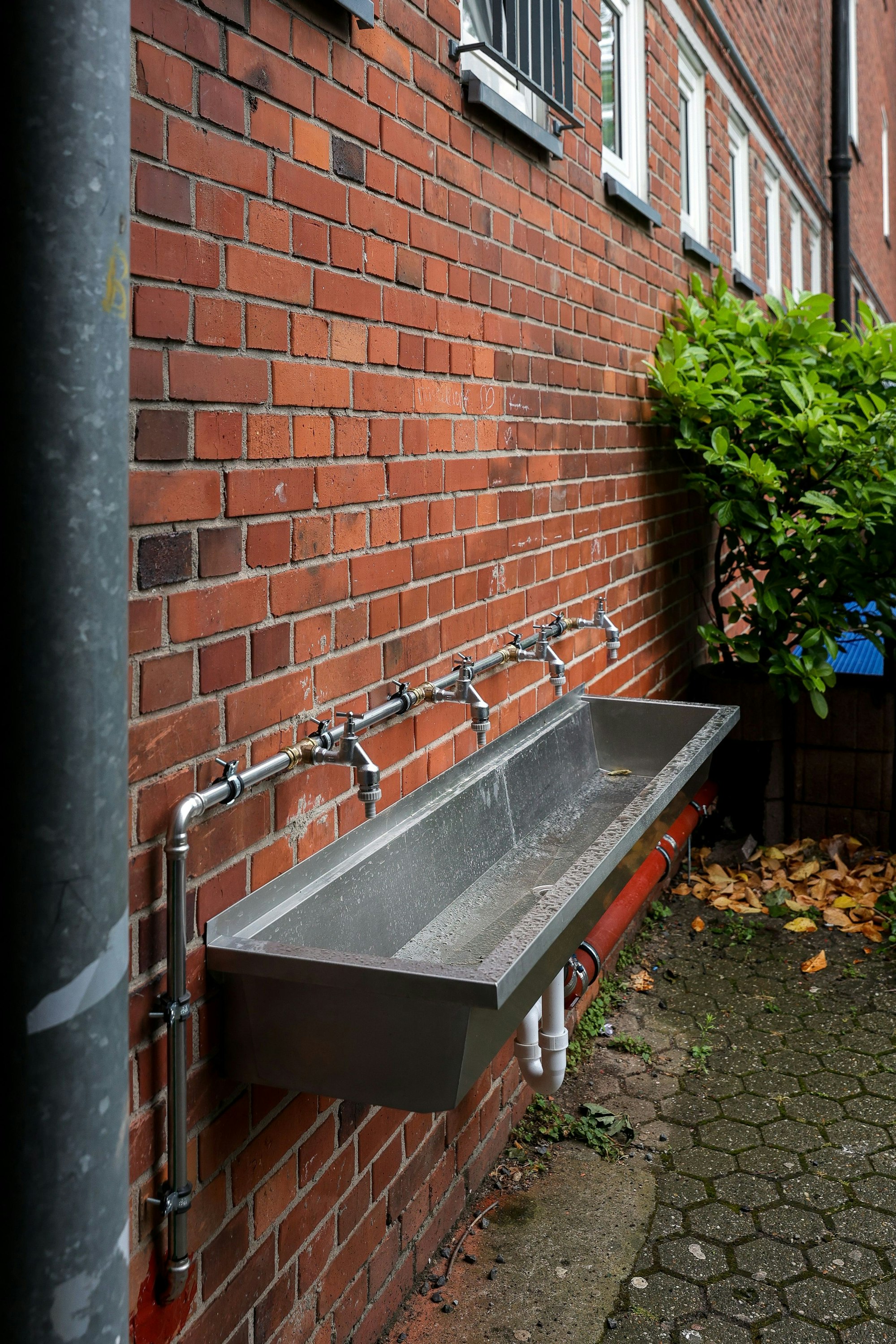 Wasserkräne und Wasserbecken auf einem Schulhof.