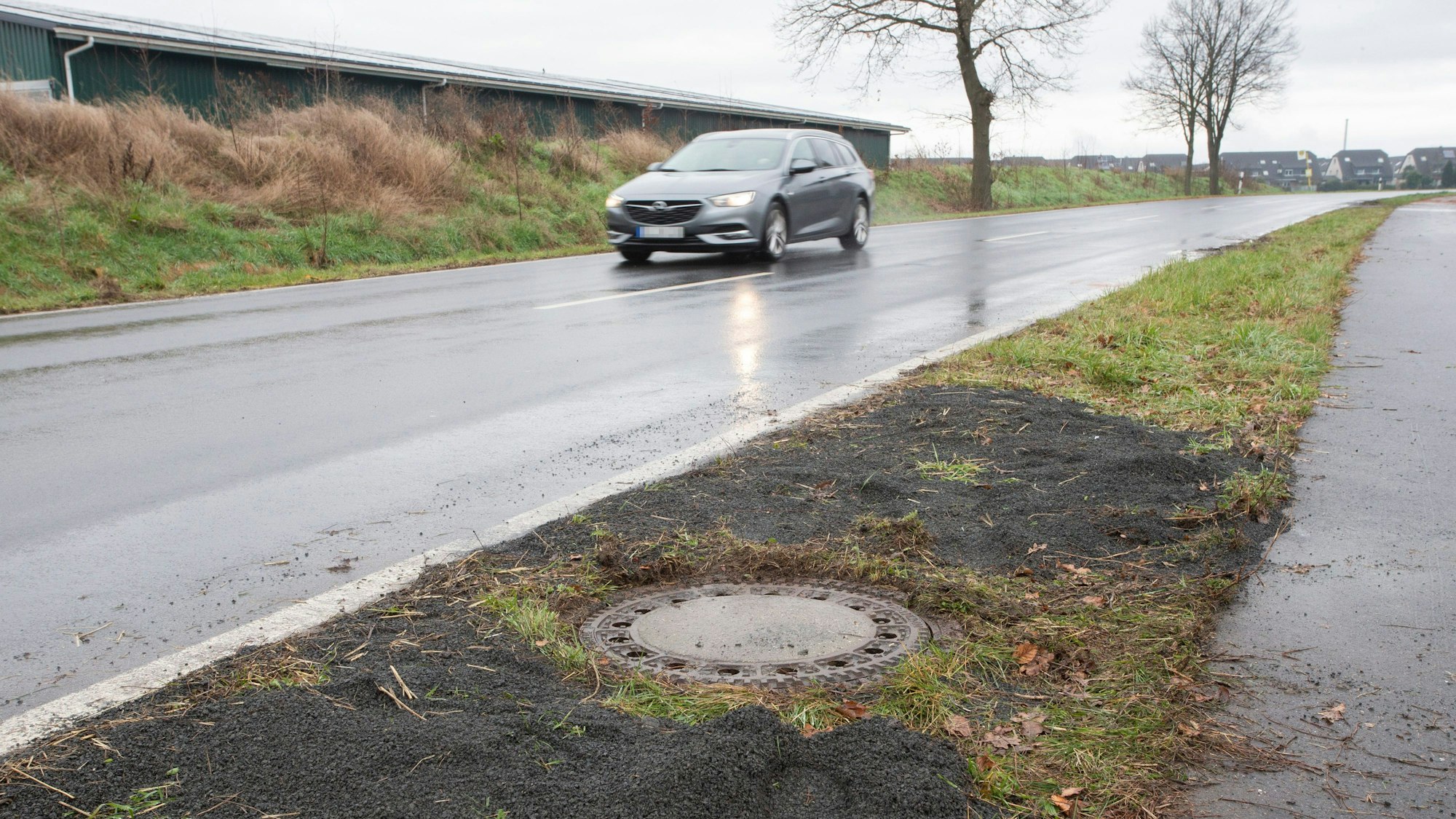 Neben einer Landstraße in Niederkassel-Lülsdorf befindet sich der Gully, in dem im März 2023 die Leiche entdeckt wurde.