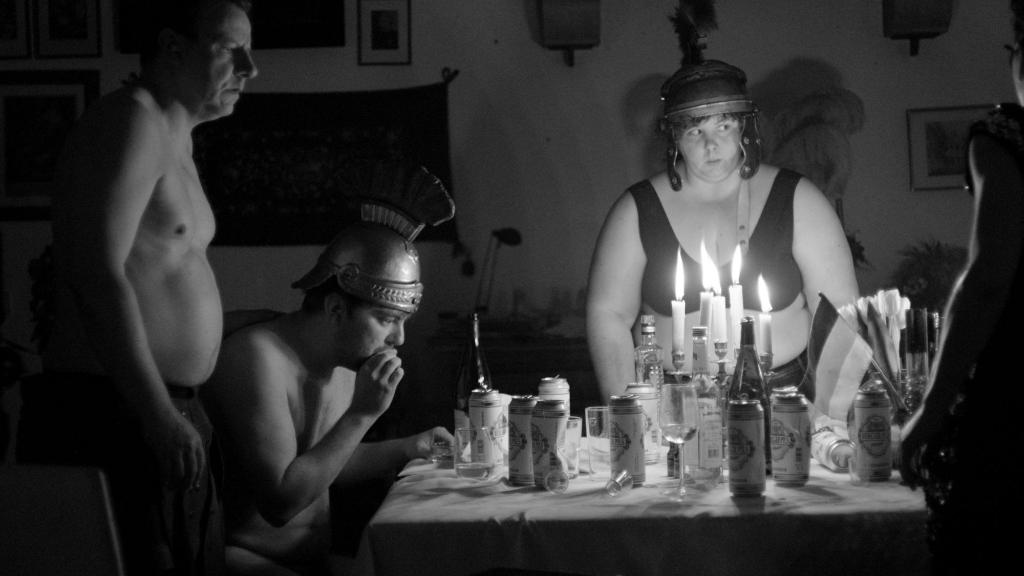 „Freiheit ist das Einzigste, was zählt - Düsseldorf steht Kopf“: Schwarz-weiß: Freya (Thekla Fliesberg), Karl (Jan Eichberg) und Dietrich (Ronald Kukulies) feiern am Tisch mit Bier.