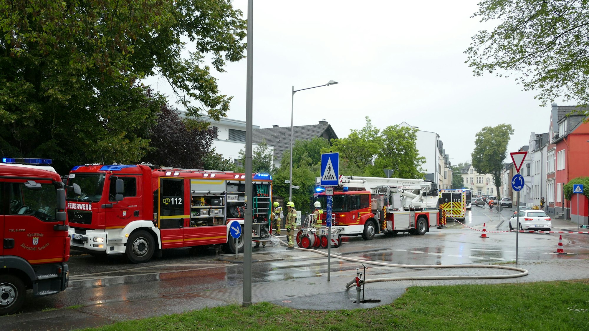 Zahlreiche Einsatzwagen der Feuerwehr stehen auf einer Straße.