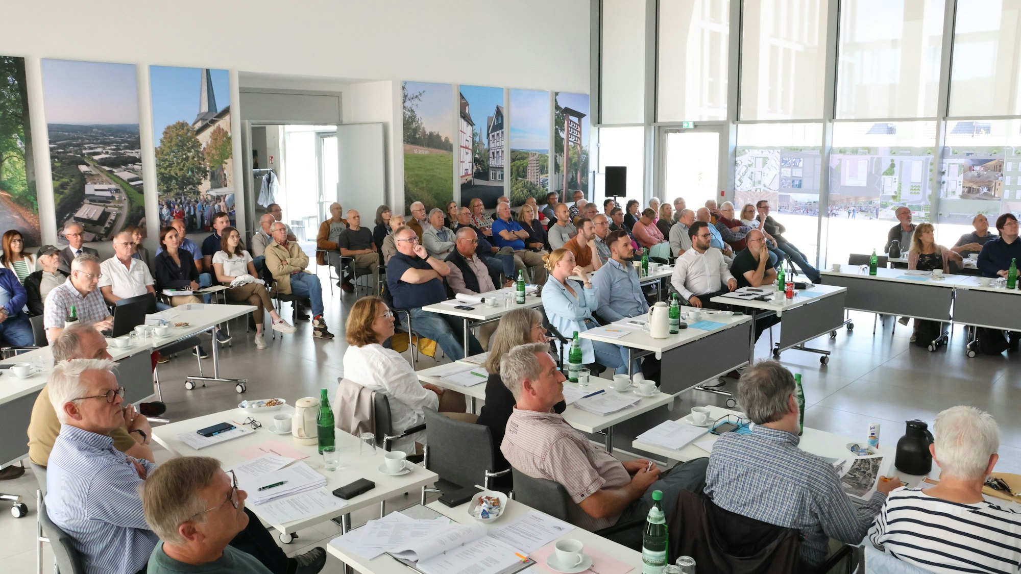 Zahlreiche Zuhörer sitzen in einem Ratssaal.