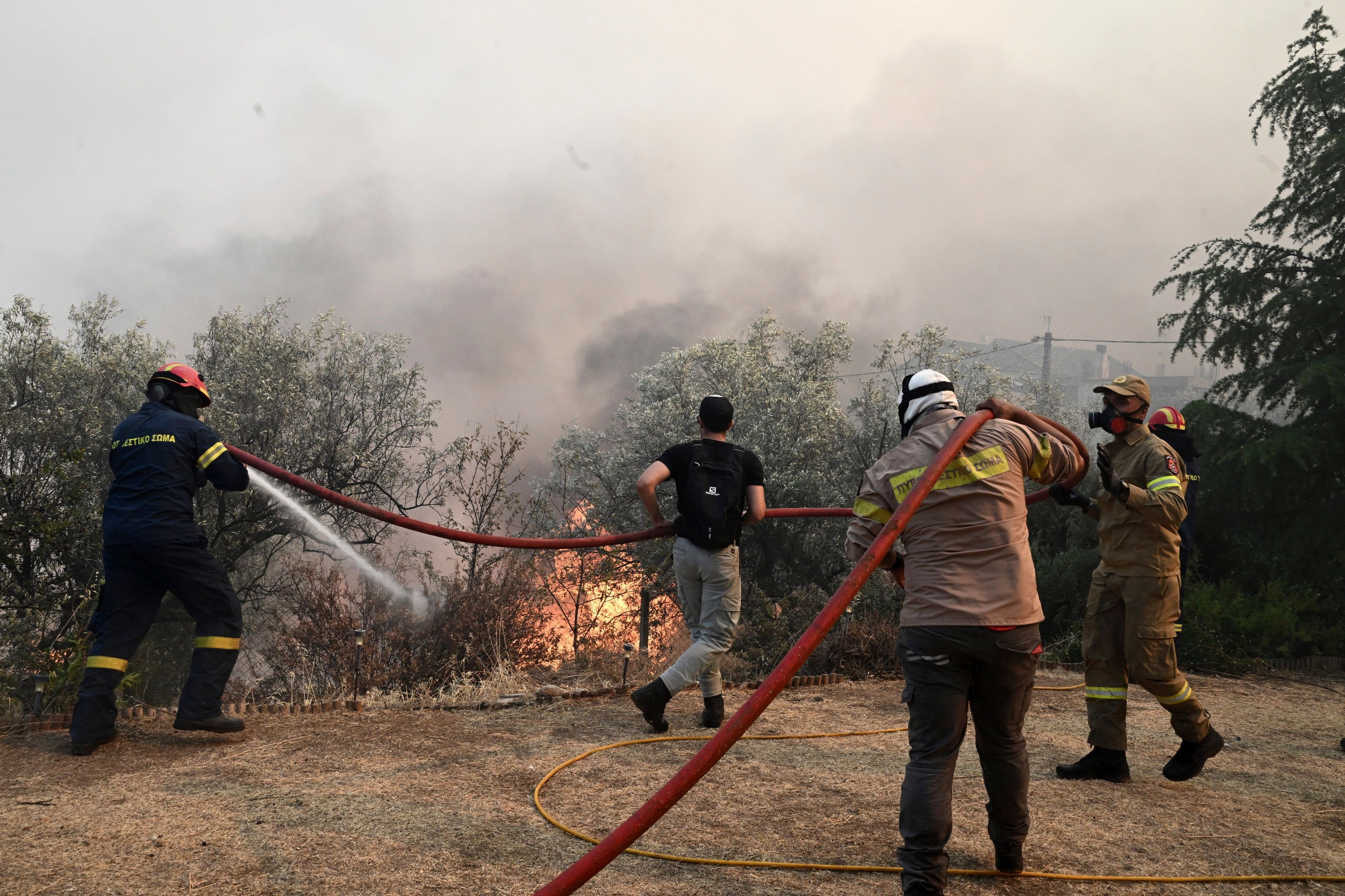 27.07.2023, Griechenland, Nea Anchialos: Feuerwehrleute und Freiwillige versuchen einen Flächenbrand zu löschen.