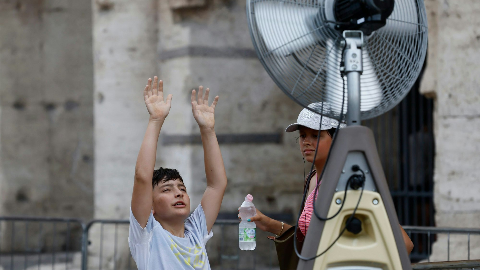 19.07.2023, Italien, Rom: Ein Junge kühlt sich vor einem Ventilator in der Nähe des Kolosseums ab. Die Temperaturen in weiten Teilen Südeuropas liegen weiterhin bei über 40 Grad Celsius. Foto: Cecilia Fabiano/LaPresse/AP/dpa +++ dpa-Bildfunk +++
