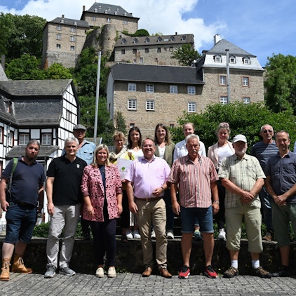 Mehrere Frauen und Männer in Wanderkleidung in einer Stadt mit mittelalterlicher Bebauung.