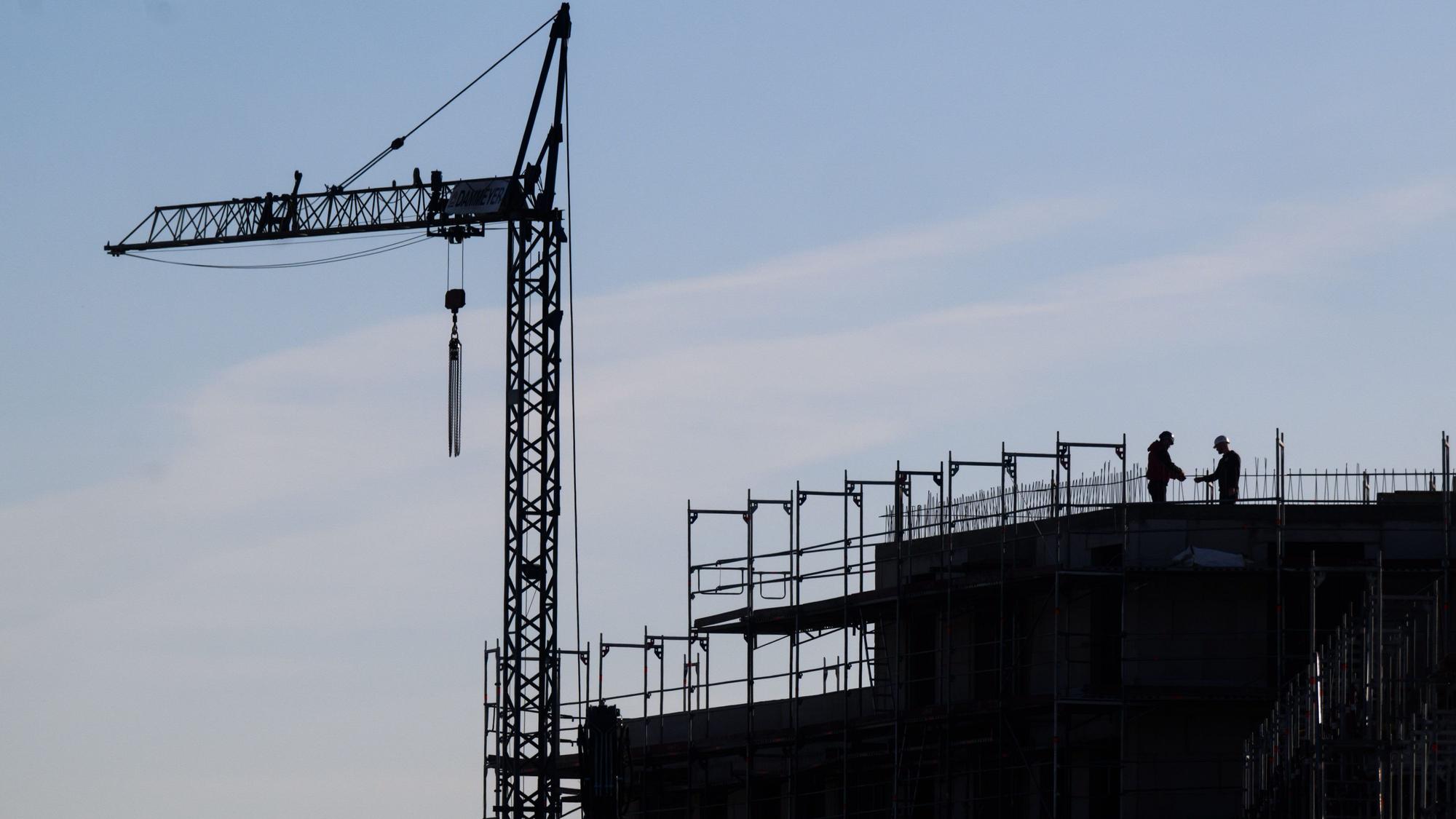 Bauarbeiter stehen auf der Baustelle eines Mehrfamilienhauses. Die deutsche Wirtschaftsleistung könnte dem Internationalen Währungsfonds zufolge in diesem Jahr leicht sinken.