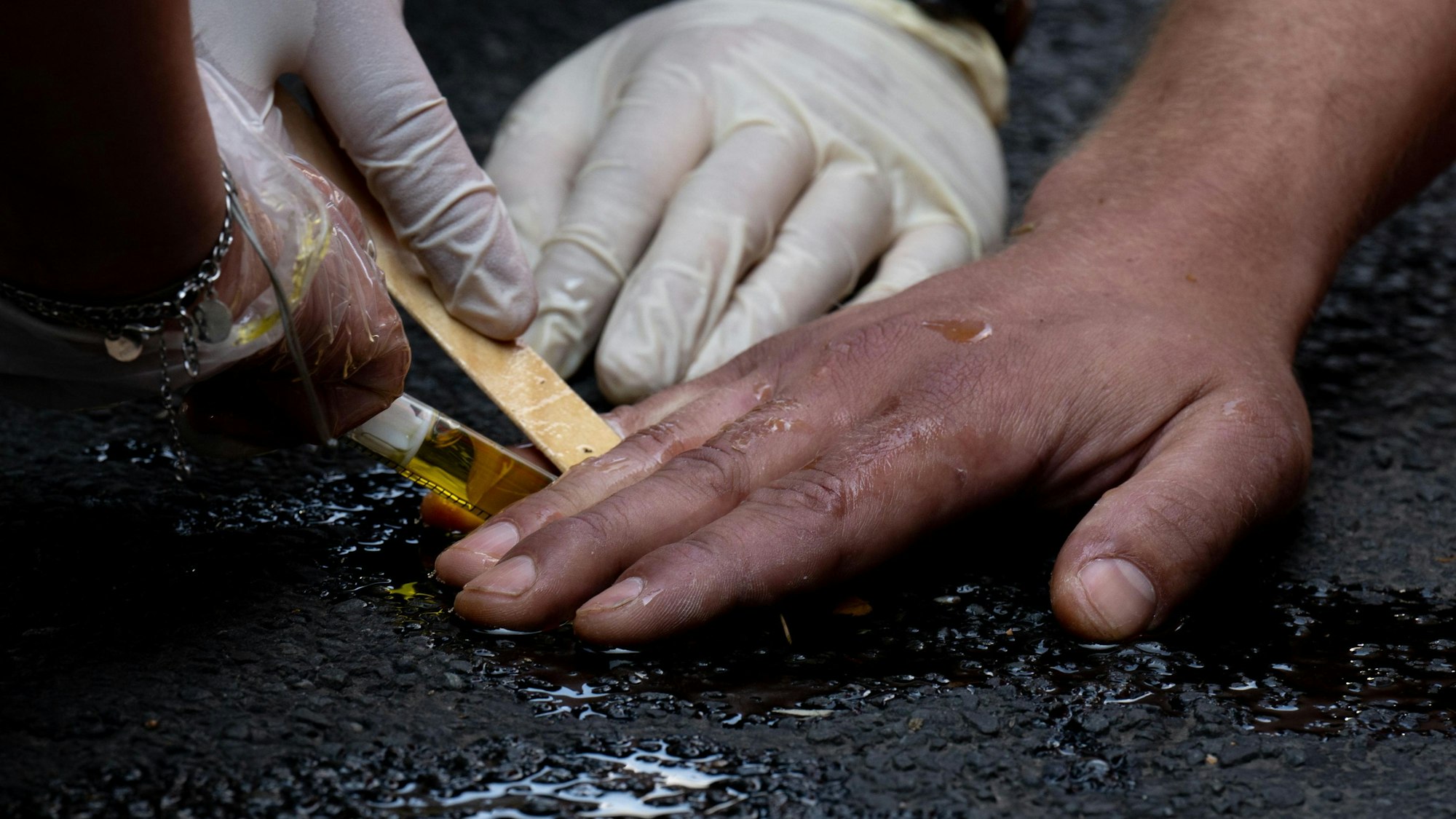 Polizeibeamte entfernen die festgeklebte Hand eines Klimaaktivisten der Gruppe „Letzte Generation“ mit Olivenöl von einer Straße. Nur wenige Minuten nach dem Freispruch für fünf Mitglieder der „Letzten Generation“ vom Vorwurf der Nötigung haben die Klimaaktivisten eine Hauptverkehrsstraße blockiert. Zehn Frauen und Männer setzten sich auf eine Kreuzung und protestierten gegen die Folgen der Klimakrise.