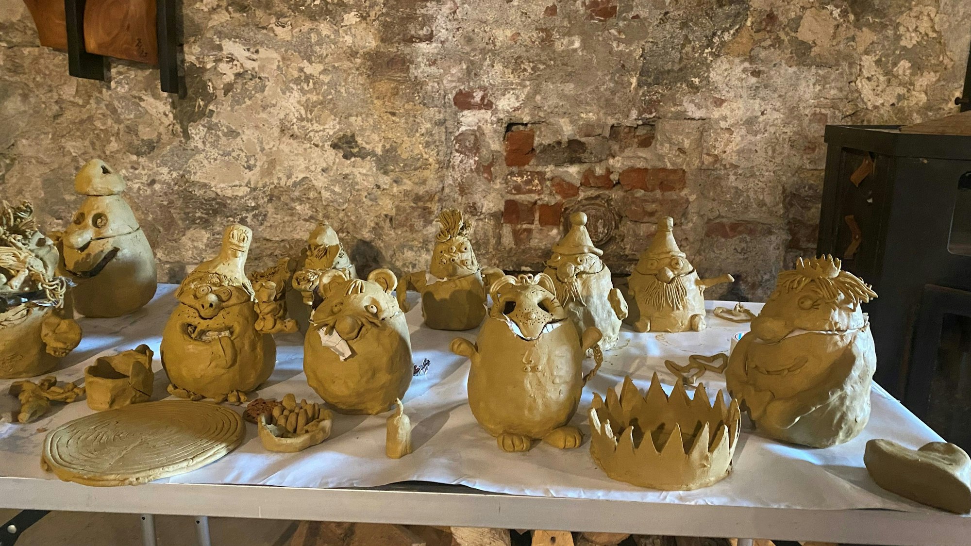 Fantasievögel und Mutmacher aus Lehm stehen auf einem Tisch.