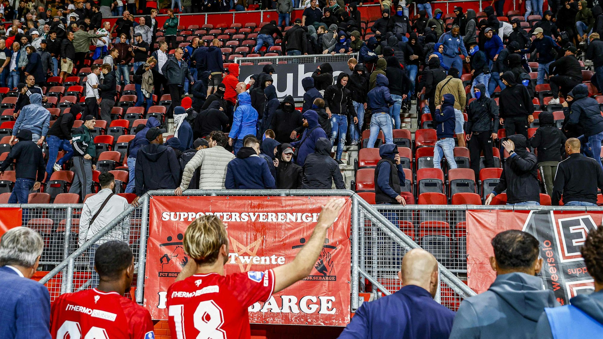 Unruhen auf der Tribüne mit Fußballspielern im Vordergrund