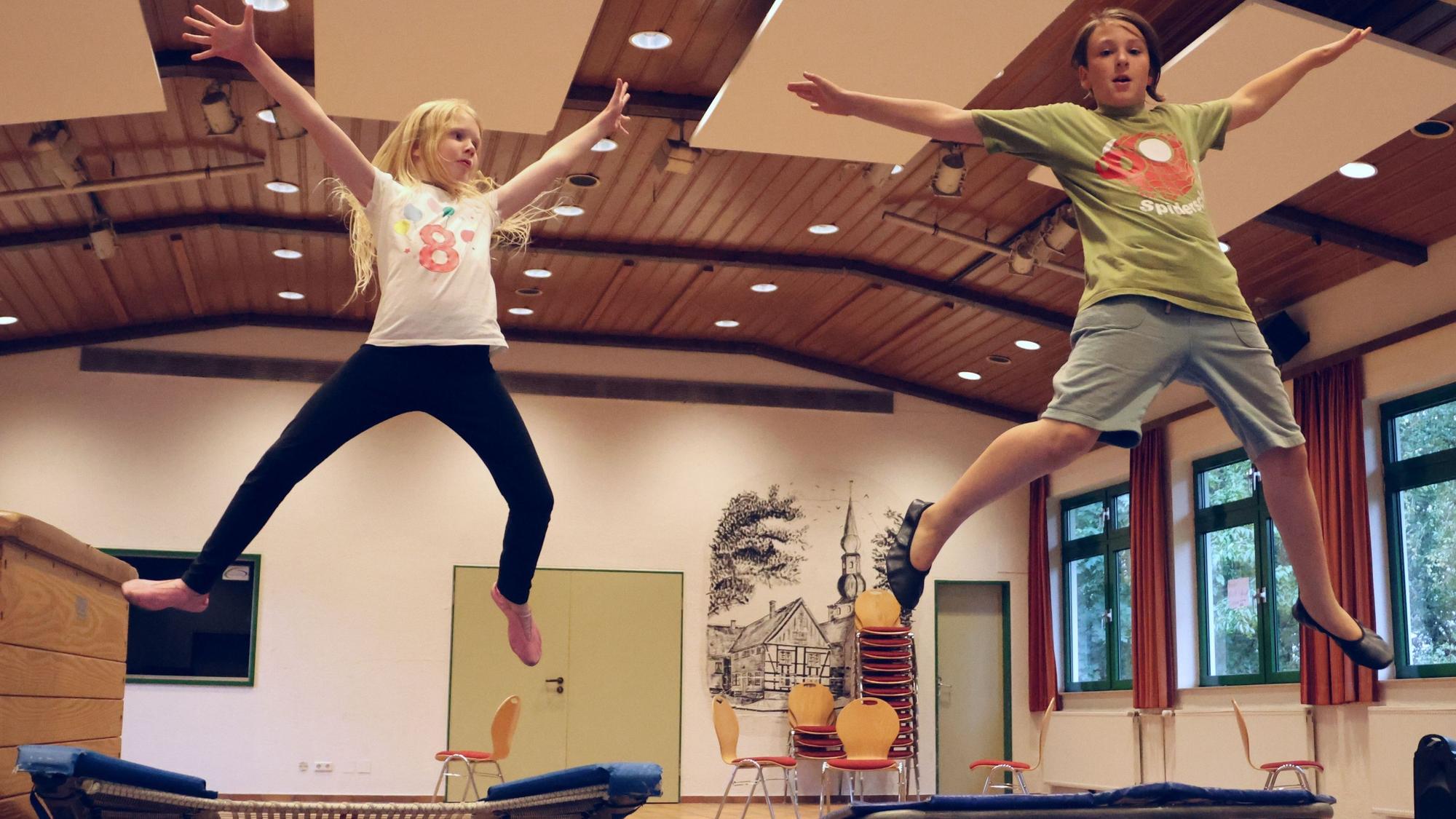 Ein Mädchen und ein Junge springen Trampolin.