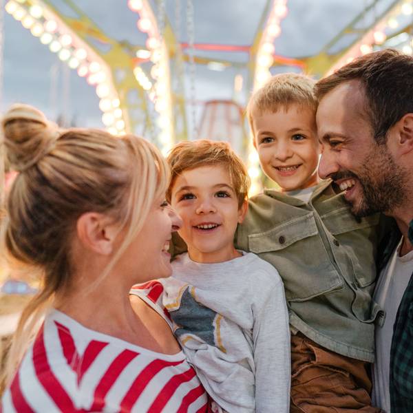 Eine Familie mit Vater, Mutter und Kindern freut sich auf einem Volksfest.