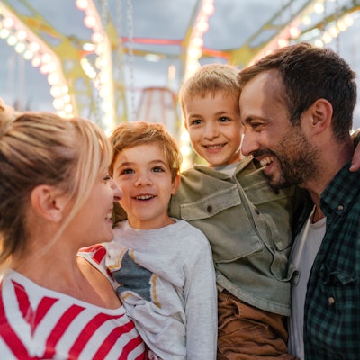 Eine Familie mit Vater, Mutter und Kindern freut sich auf einem Volksfest.