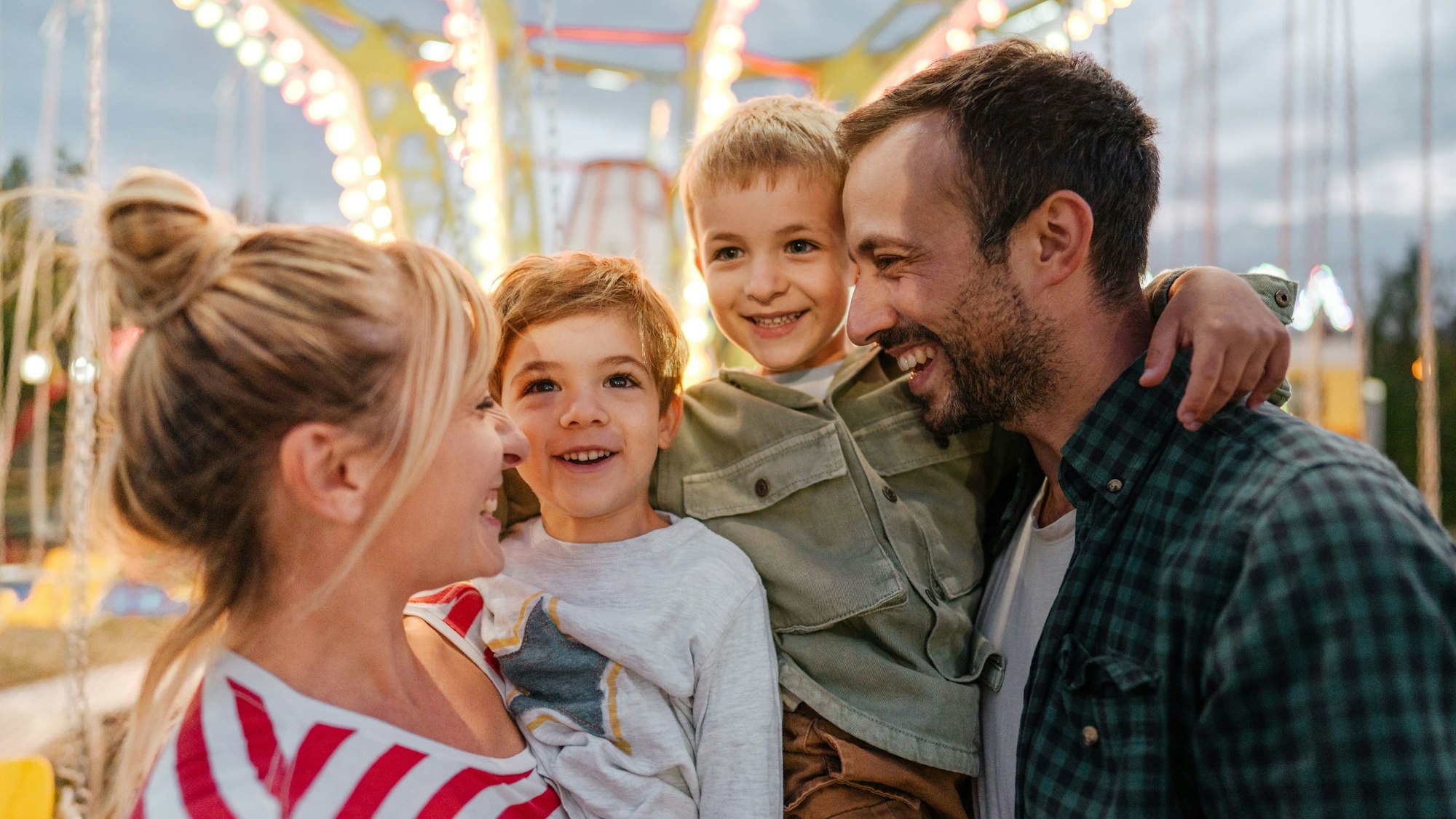 Eine Familie mit Vater, Mutter und Kindern freut sich auf einem Volksfest.