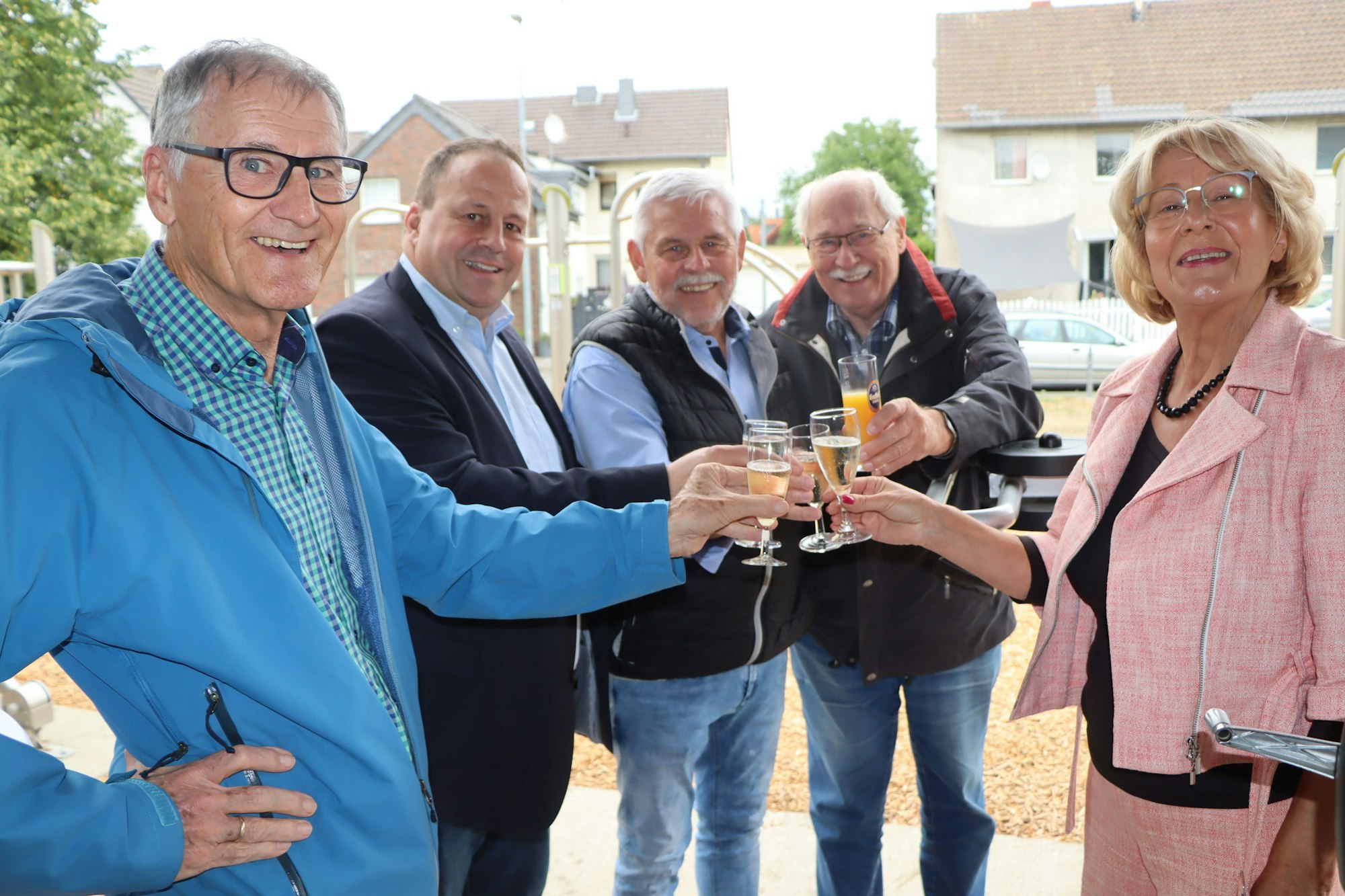 Vier Männer und eine Frau stoßen mit ihren Sektgläsern an.