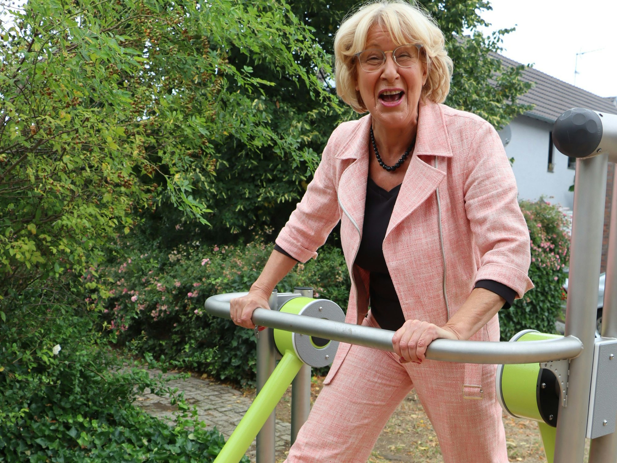 Eine Frau im Hosenanzug macht Sport auf einem Gerät.