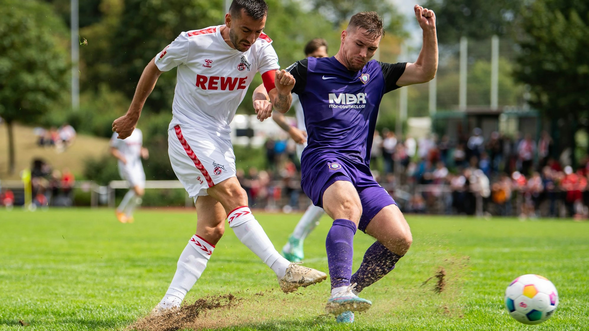 Das Bild zeigt einen Schuss von Sargis Adamyan. Der Rasen spritzt nach oben.