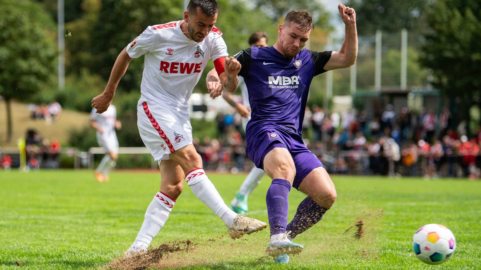 Das Bild zeigt einen Schuss von Sargis Adamyan. Der Rasen spritzt nach oben.