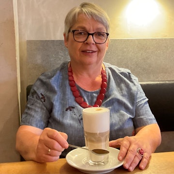 Grauhaarige Frau im Café mit Latte Macchiato