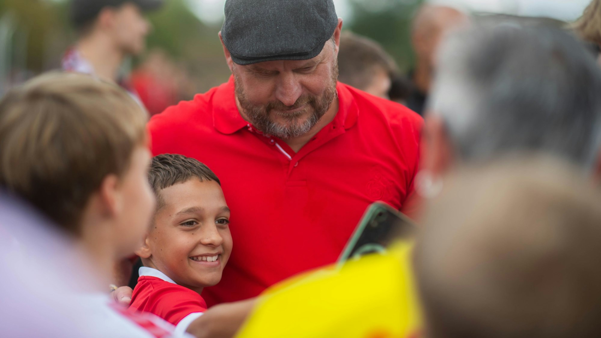 Das Bild zeigt Steffen Baumgart, der sich von einem jungen FC-Fan fotografieren lässt.