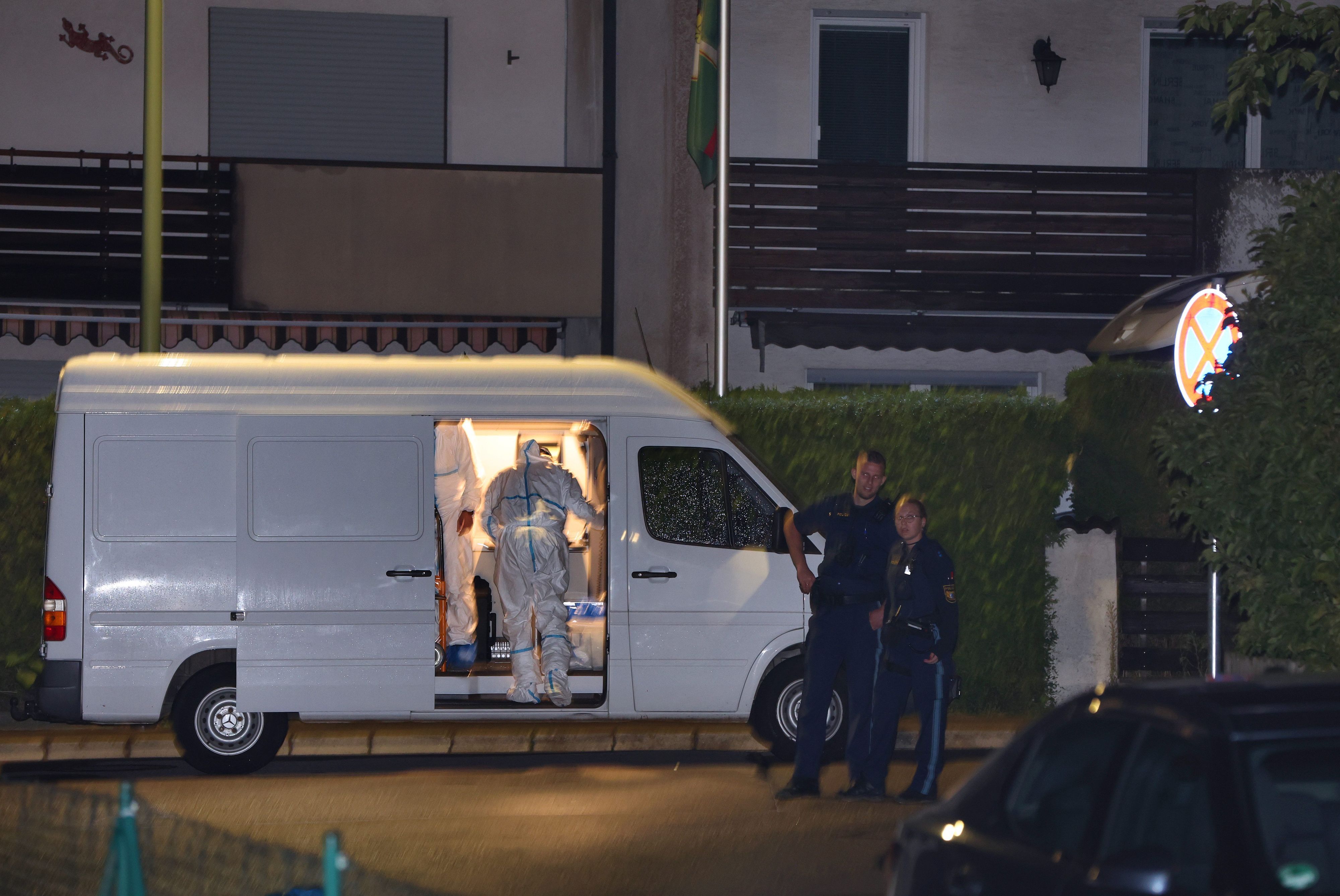 Polizisten und Beamte der Spurensicherung stehen in der Nähe eines Hauses, in dem drei Menschen erschossen wurden.