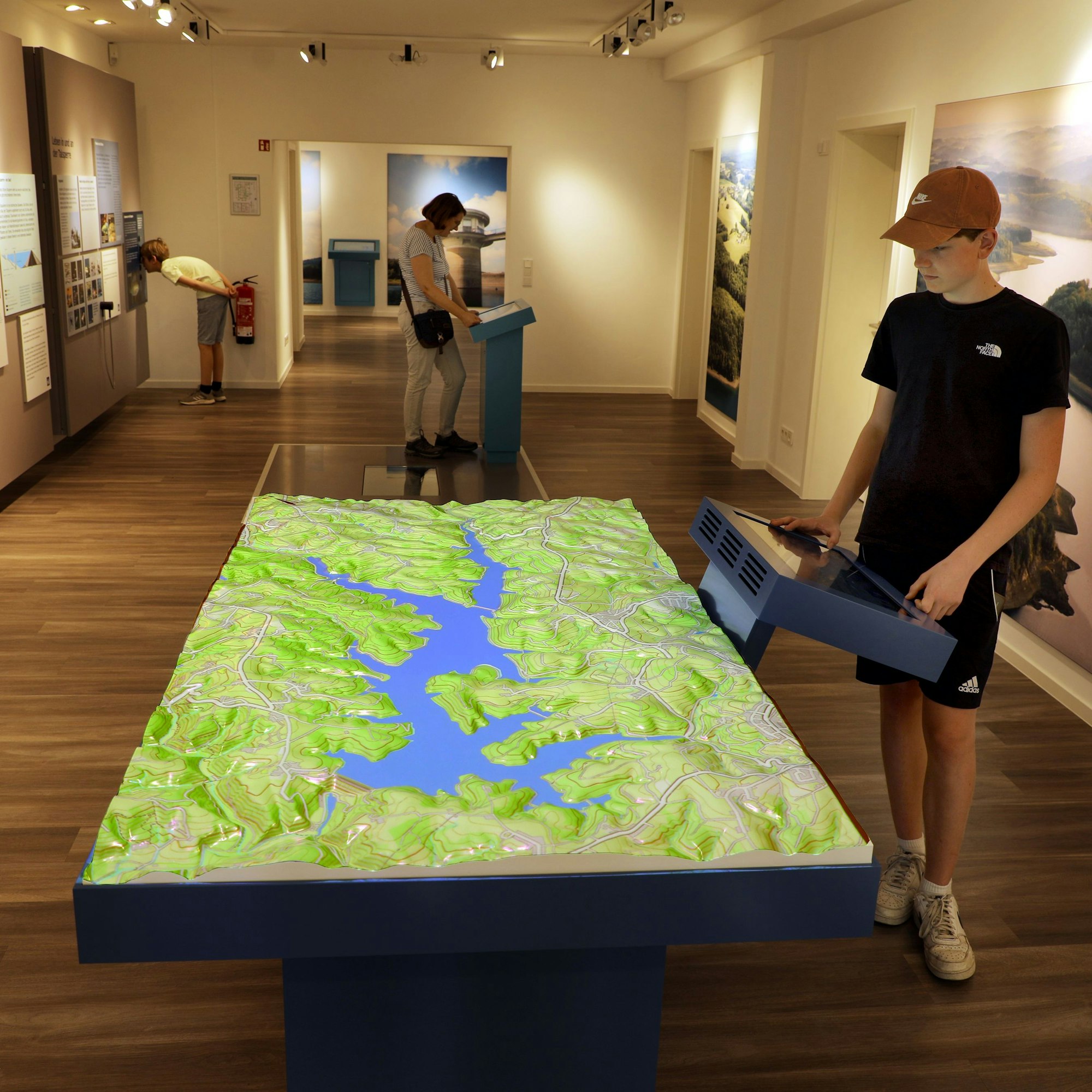 Menschen stehen an Leuchtpulten und Vitrinen einer Ausstellung.