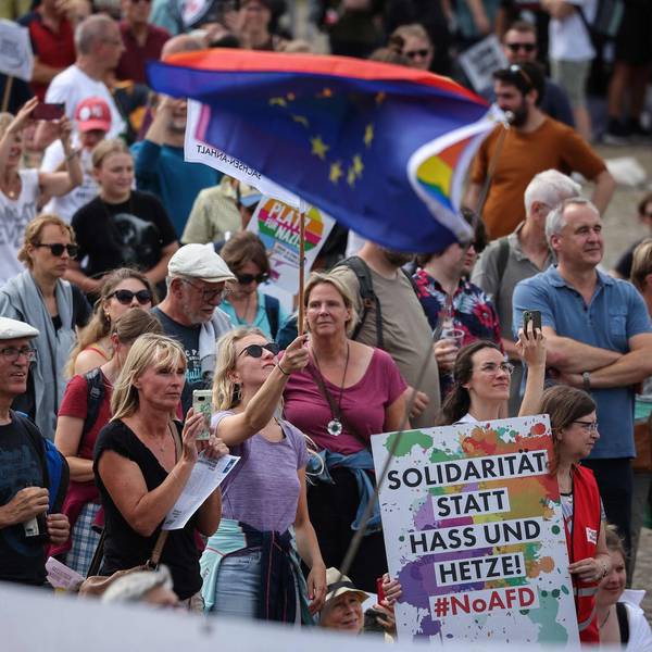 Gegendemonstranten beim Europaparteitag der AfD in Magdeburg schwenken die Europafahnen und zeigen ein Plakat mit der Aufschrift "Solidarität statt Hass und Hetze".