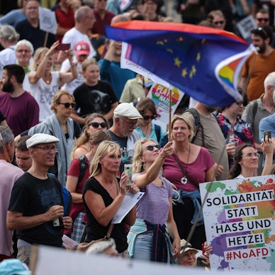 Gegendemonstranten beim Europaparteitag der AfD in Magdeburg schwenken die Europafahnen und zeigen ein Plakat mit der Aufschrift "Solidarität statt Hass und Hetze".