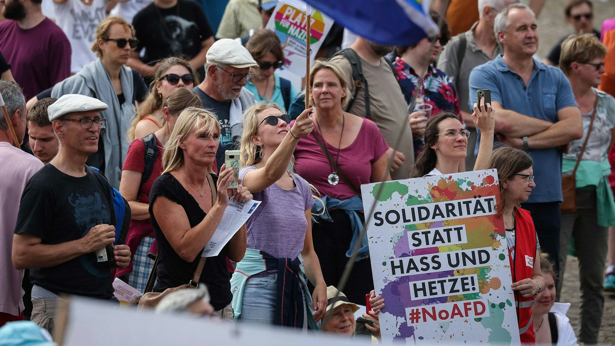 Gegendemonstranten beim Europaparteitag der AfD in Magdeburg schwenken die Europafahnen und zeigen ein Plakat mit der Aufschrift "Solidarität statt Hass und Hetze".