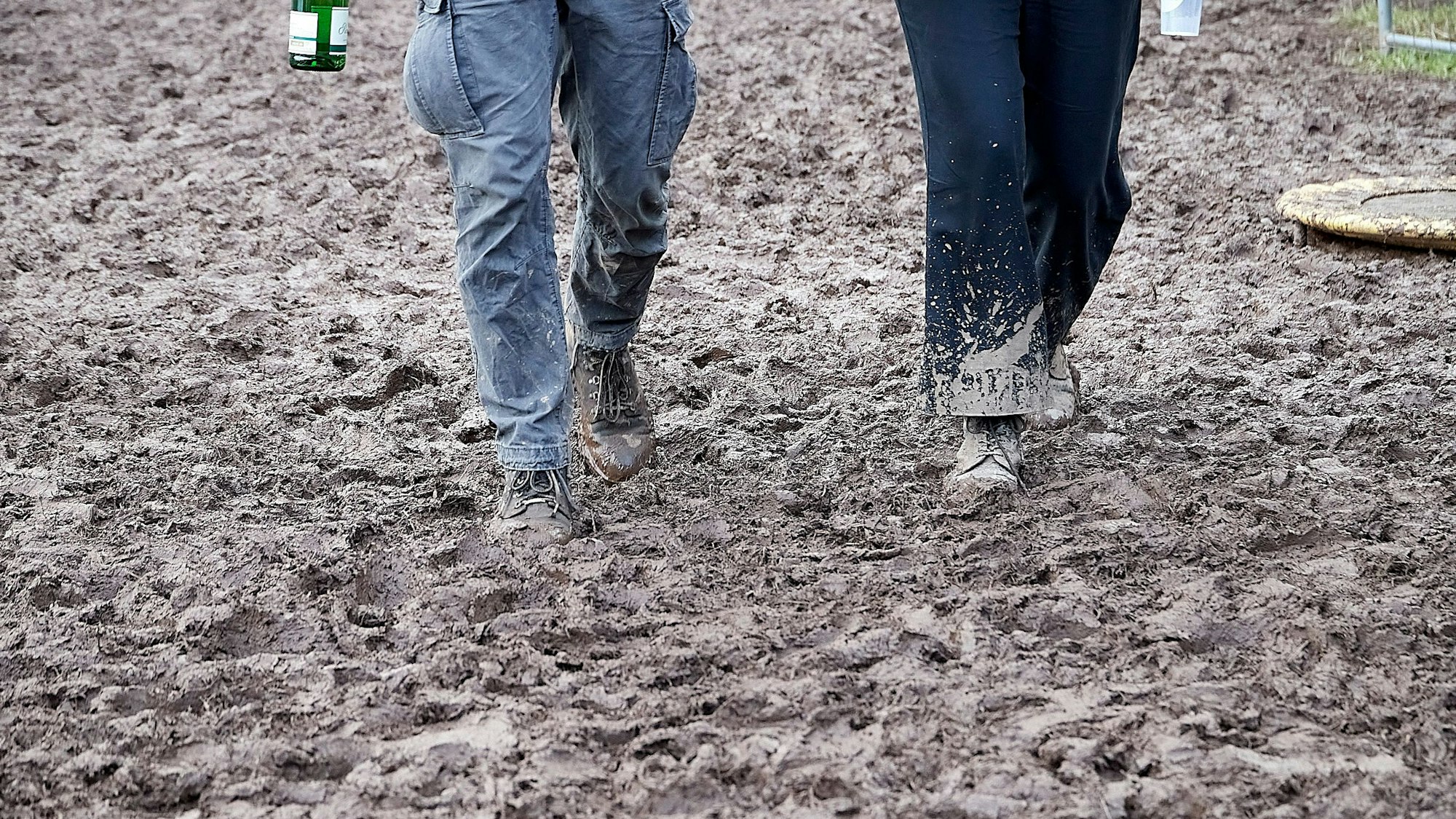 Zwei Menschen gehen auf einem sehr matschigen Weg.