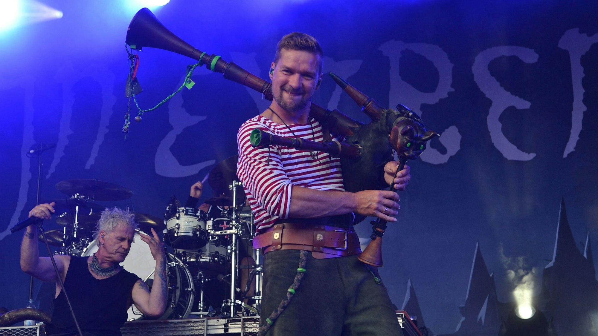 Ein Mann steht mit einem Dudelsack auf einer Konzertbühne.