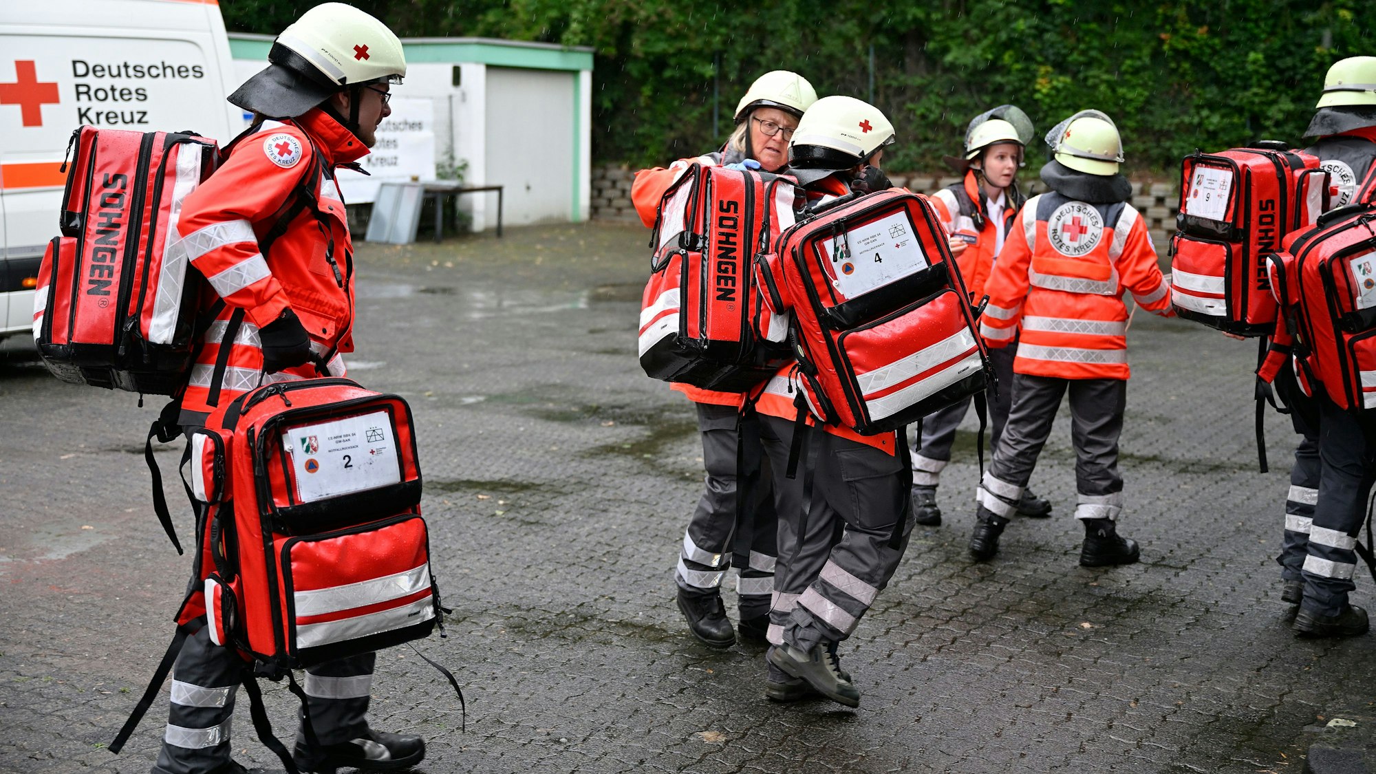 Rettungssanitäter des Deutschen Roten Kreuzes tragen Rettungsrucksäcke zur Einsatzstelle.