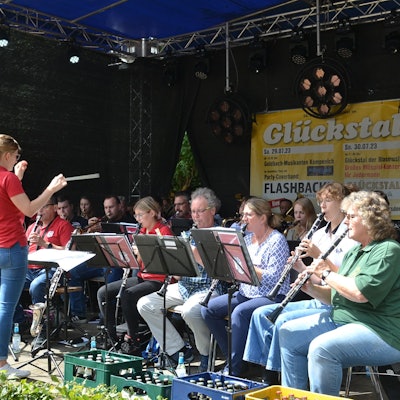 Das Foto zeigt eine Dirigentin vor einem Orchester.