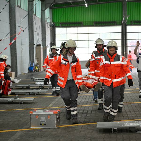 Rettungssanitäter bringen Verletzte auf einer Trage zu einem Behandlungsplatz, Ärzte versorgen Schwerverletzte sofort an Ort und Stelle.