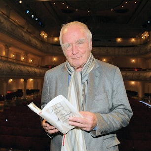 Martin Walser hält im Erfurter Kaisersaal ein aufgeschlagenes Buch in den Händen und schaut in die Kamera.
