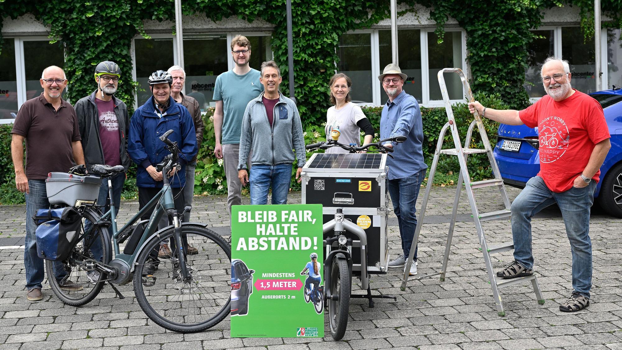 Die Beteiligten stehen um ein Abstands-Schild herum.