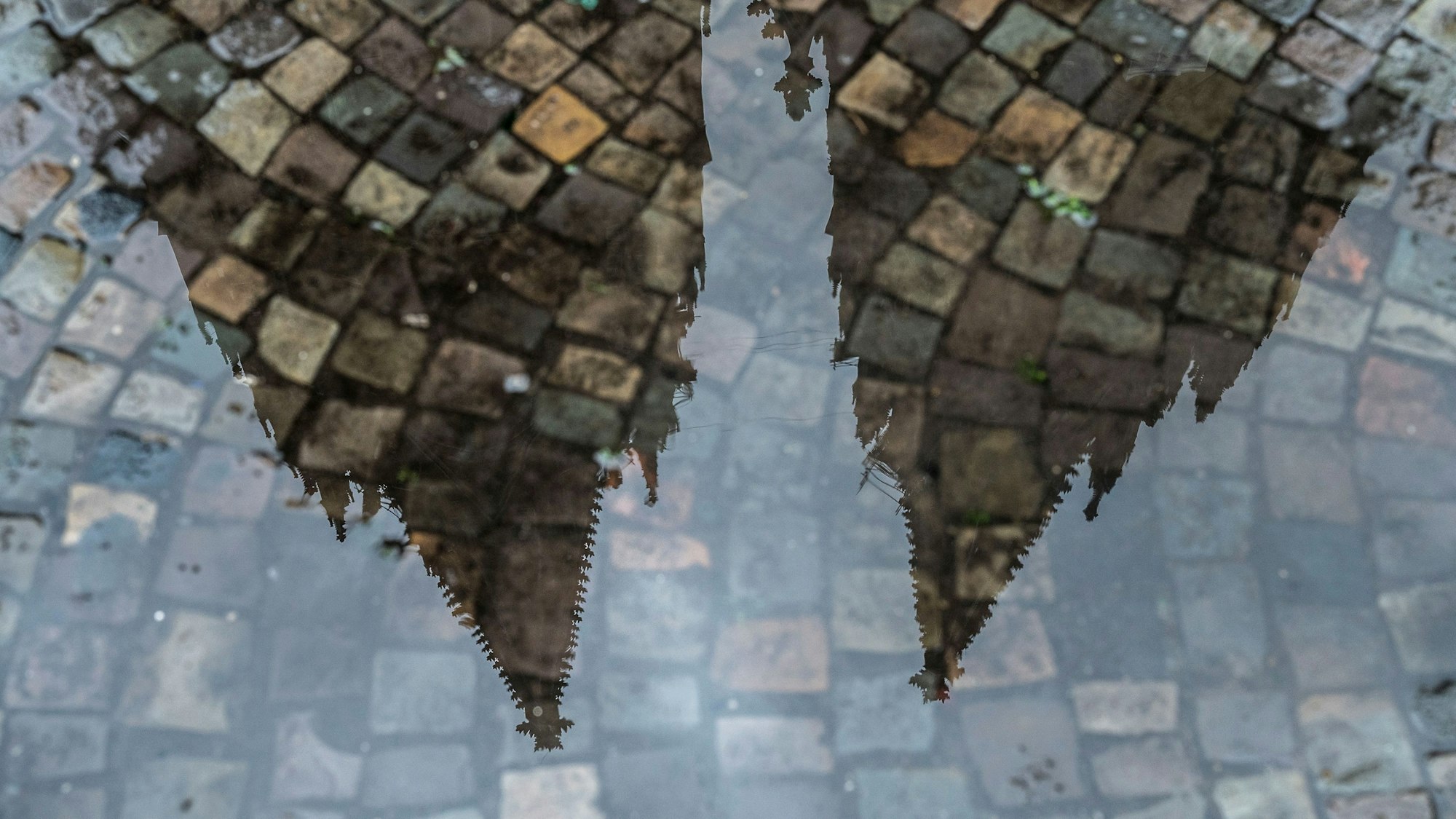 Der Kölner Dom spiegelt sich in einer Pfütze.