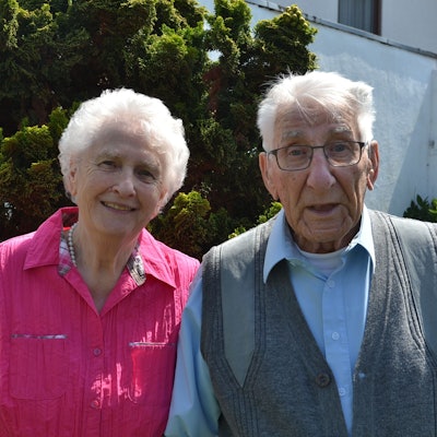 Das hochbetagte Paar blickt lächelnd in die Kamera.
