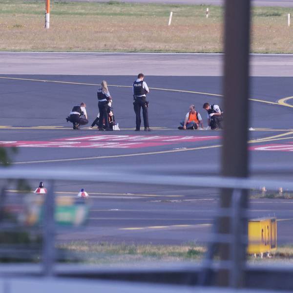 Düsseldorf: Polizisten stehen auf dem Flugfeld und versuchen Aktivisten der Gruppe Letzte Generation am Flughafen vom Asphalt zu lösen, nachdem diese sich festgeklebt hatten.