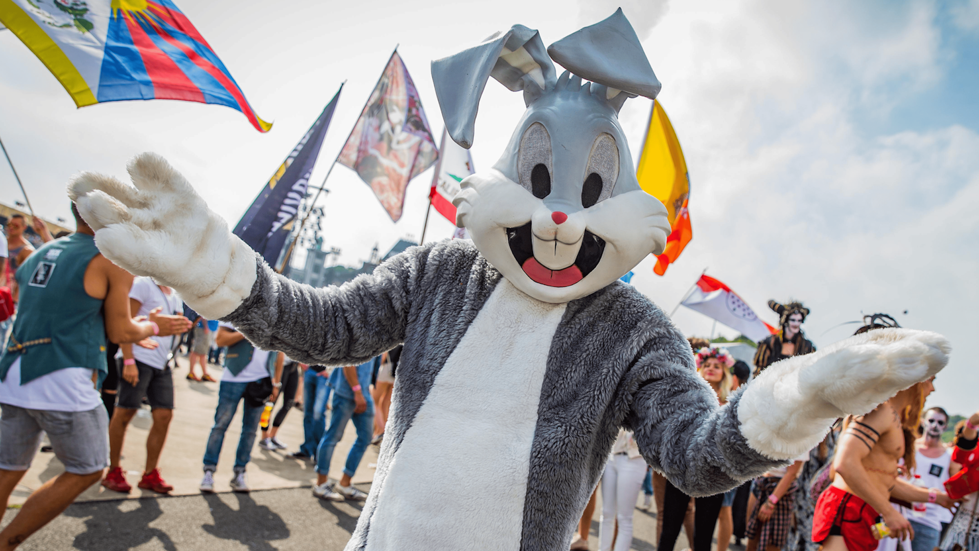 Ein Animateur im Hasenkostüm. Im Hintergrund wehen viele bunten Fahnen.