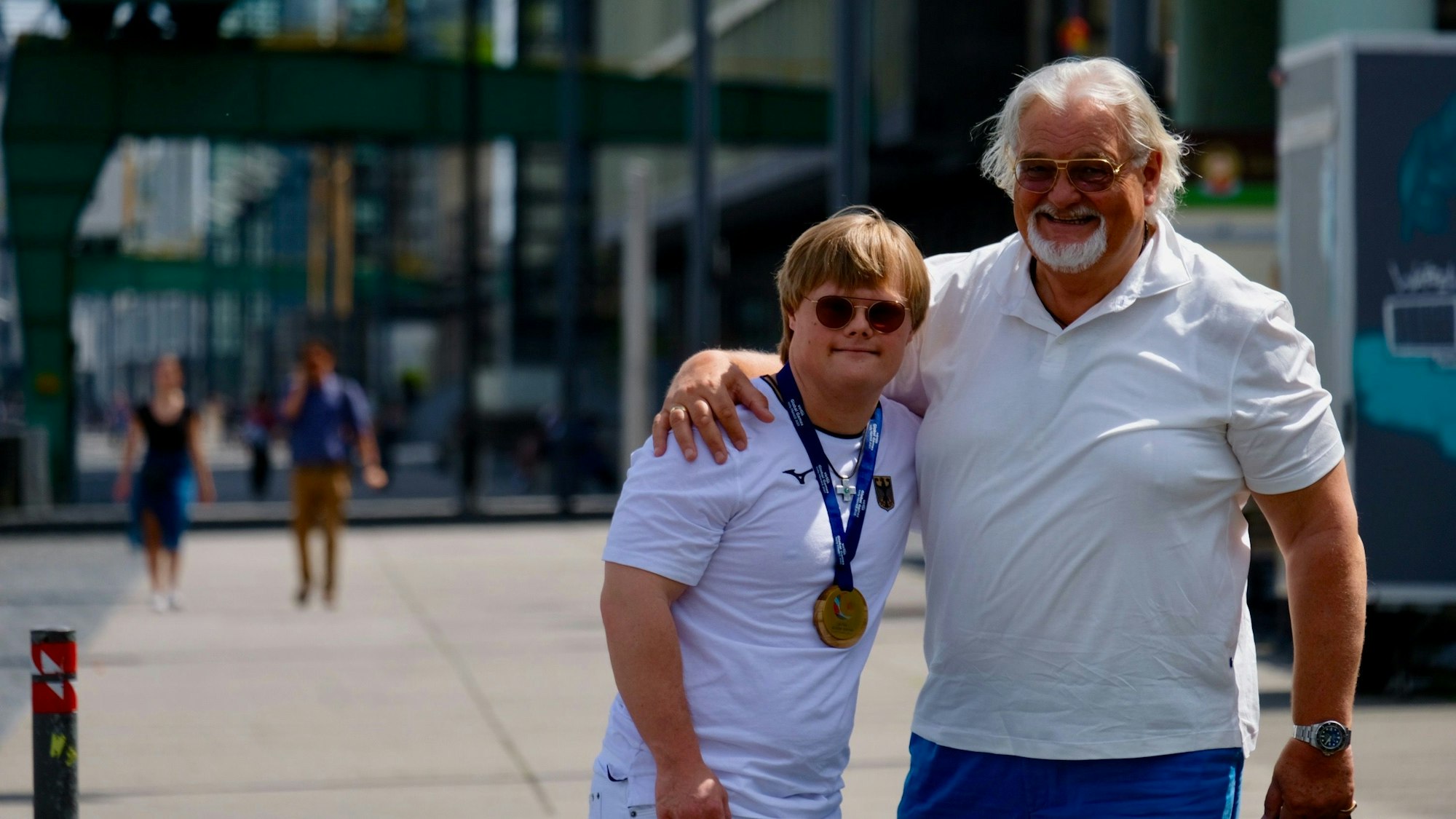 Der Sportler trägt seine goldene Medaille, sein Vater hält ihn im Arm.