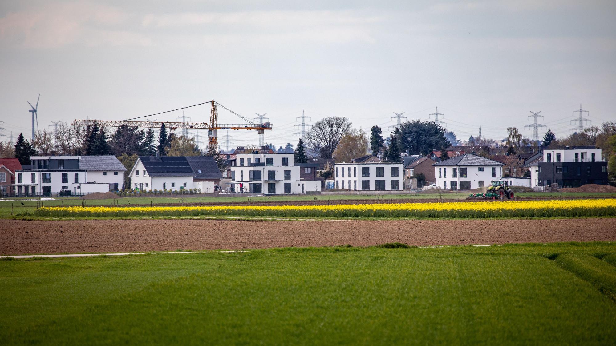 16.04.2021, Pulheim: Neu errichtete Wohnhäuser stehen am Ortsrand des Ortsrandes von Sinnersdorf während im Vordergrund landwirtschaftliche Felder zu sehen sind. Die Nachfrage nach Immobilien ist groß. Einfamilienhäuser stehen dabei wegen des hohen Flächenverbrauchs in der Kritik. Foto: Matthias Heinekamp